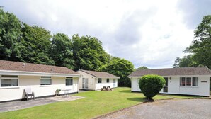 A row of white mobile homes with a grassy lawn and a gravel path in front. - 4 Rosecraddoc Lodge Holiday Bungalows (Liskeard)