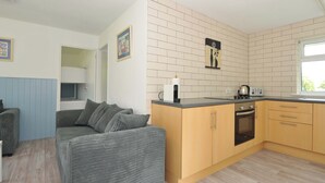 A compact kitchen with wooden cabinets, a built-in oven, and a window. - 4 Rosecraddoc Lodge Holiday Bungalows (Liskeard)