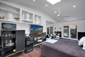 A modern bedroom with a bed, a desk, and shelves with decorative items. - West University Bungalow w/Private Studio! (Tucson)