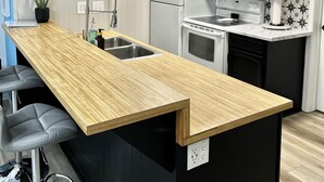 A modern kitchen with a wooden bar counter, white cabinets, a black clock, and a stainless steel sink. - JUST LISTED!!  REMODELED!!  Angel Fire 2B/2B Condo (Angel Fire)