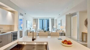 Una habitación de hotel moderna con una isla central, una zona de comedor y vistas a la ciudad.