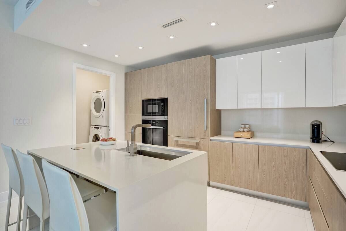 A modern kitchen with a central island, built-in appliances, and a clean, minimalist design.
