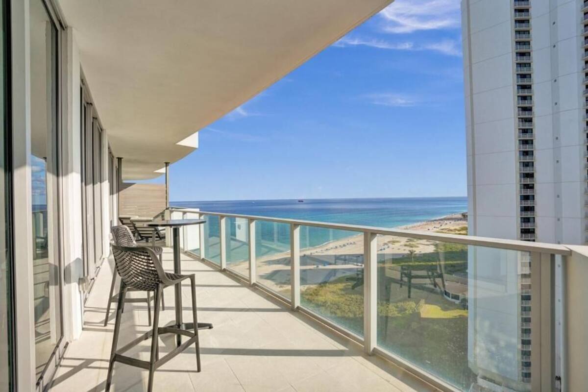 Ein Balkon mit Blick auf den Ozean, einem Tisch mit Stühlen und einem Glasgeländer.