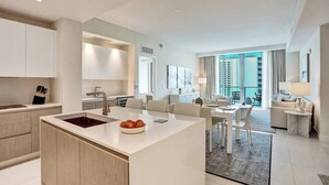 Una habitación de hotel moderna con cocina, zona de comedor y sala de estar con un amplio ventanal.