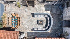 Une terrasse en pierre avec un espace salon incurvé et une cheminée intégrée.