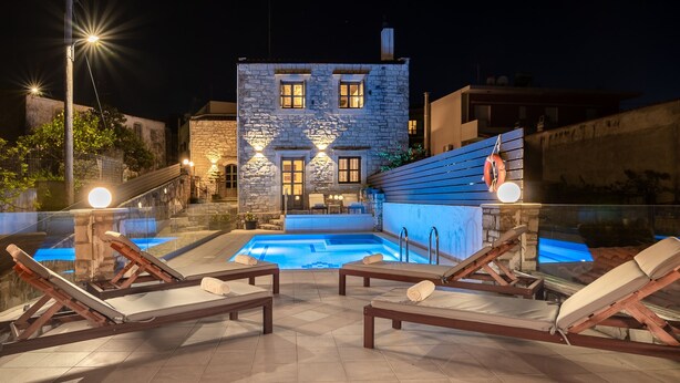 Une piscine sur le toit, avec des chaises longues, et un bâtiment en pierre en arrière-plan.
