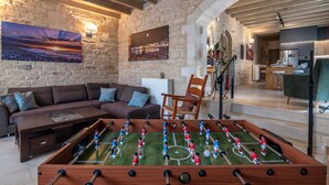 Un salon chaleureux avec un baby-foot, un canapé et un mur en pierre.