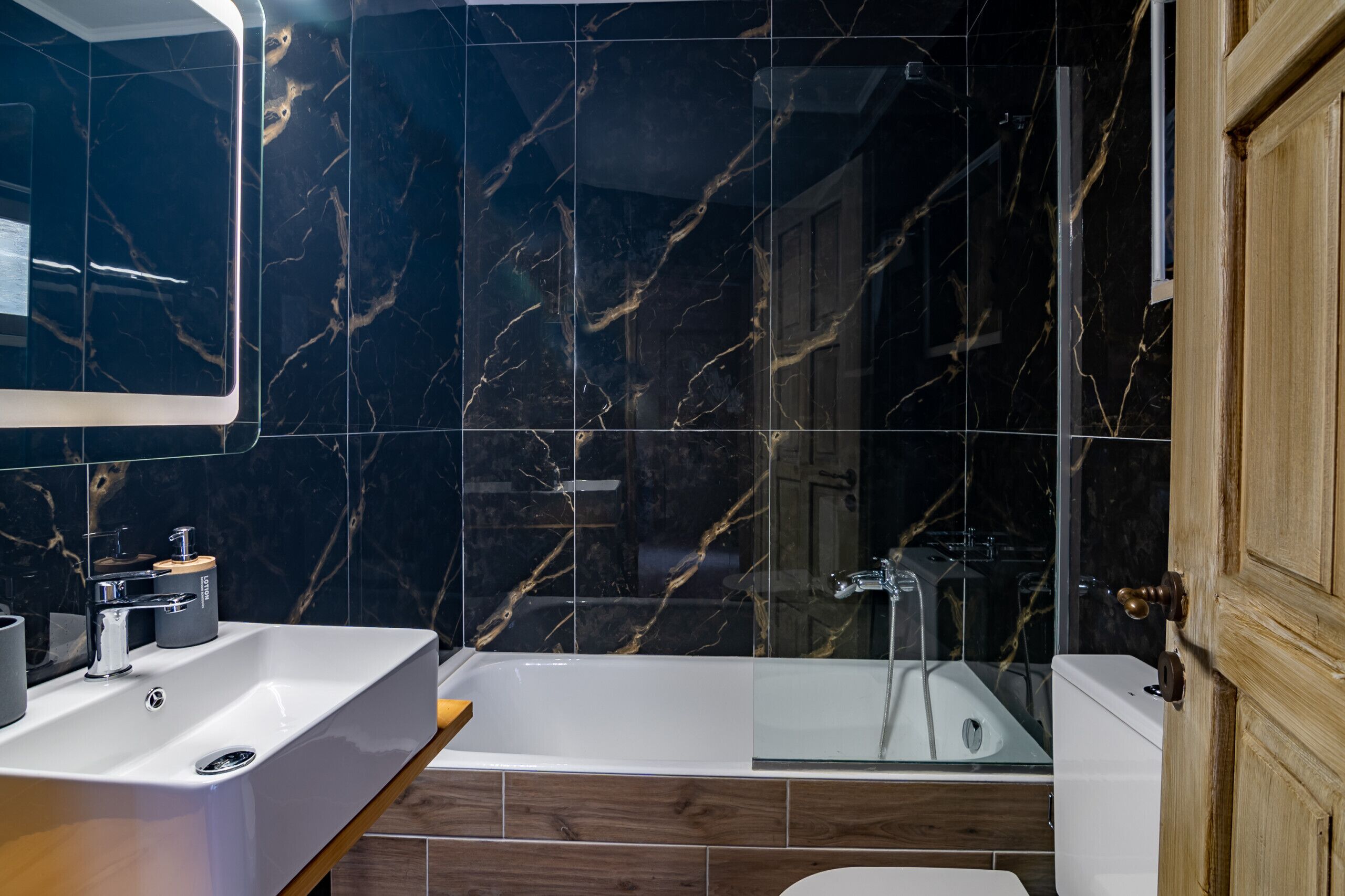 A modern bathroom with a white sink, a bathtub, and a glass shower enclosure.