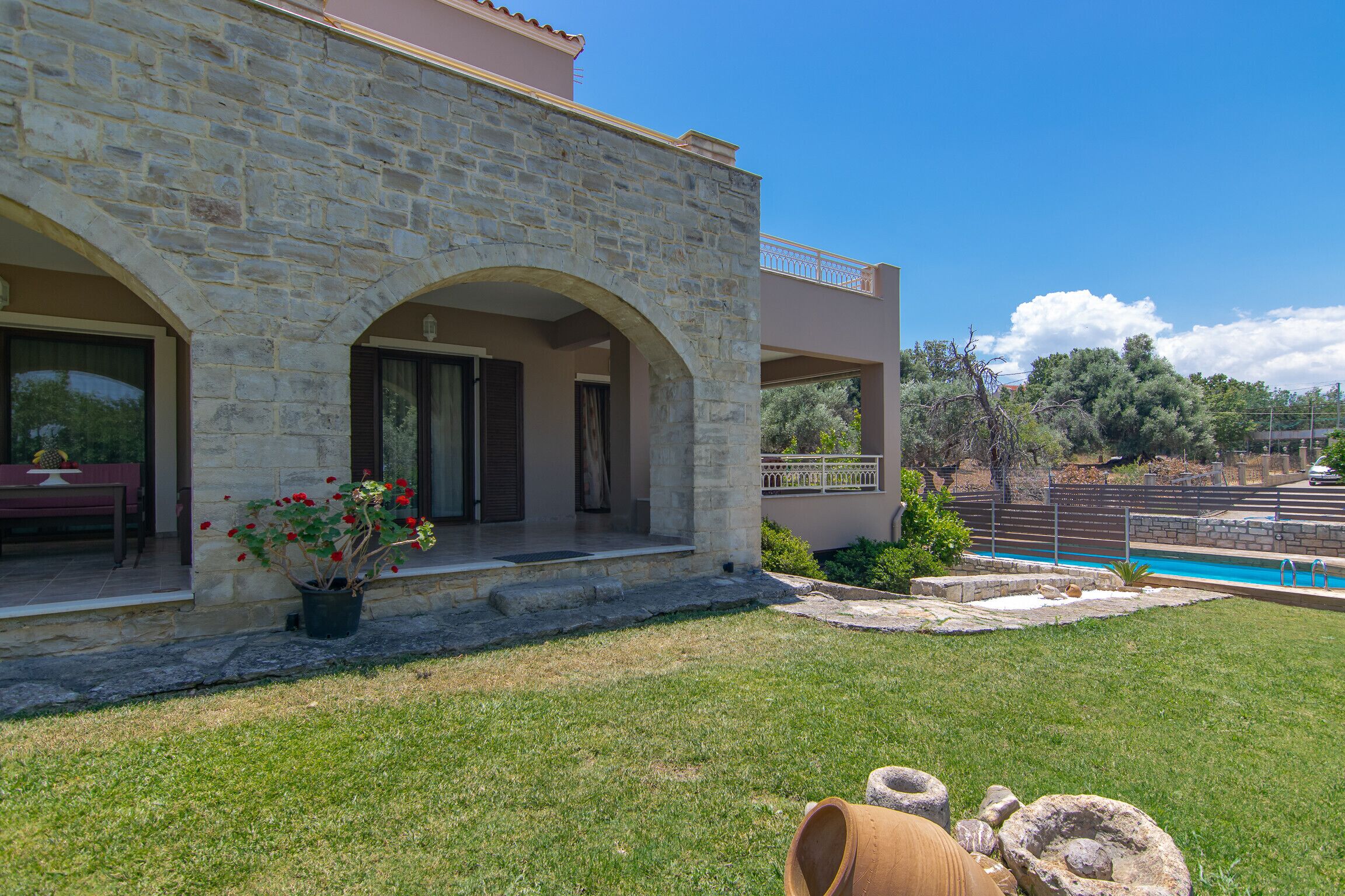 A stone building with a pool and a well-maintained lawn.