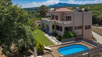 Una piscina al aire libre, sombrillas, sillones reclinables de piscina