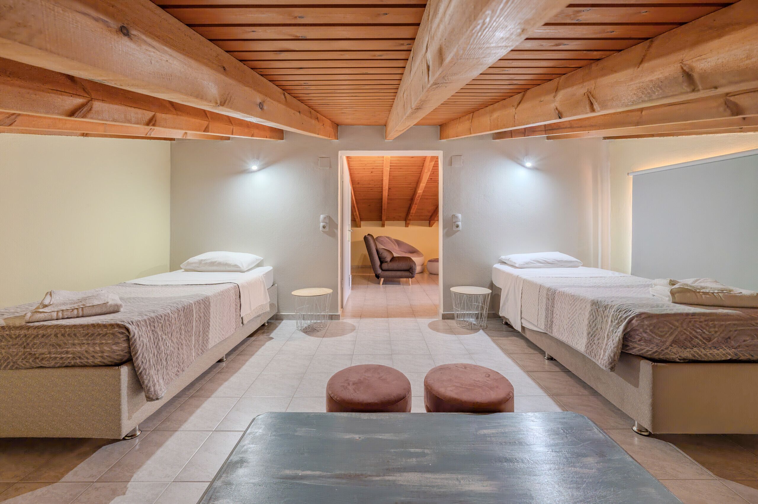 Una habitación con dos camas, un banco y una silla.