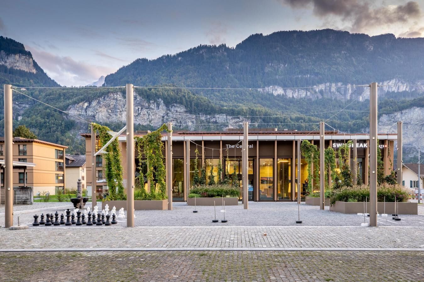 Um edifício com design moderno, com um restaurante chamado "The Central" e um letreiro para "SWISS STEAK".