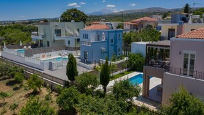 A residential area with modern houses, a swimming pool, and a mountainous backdrop. - Bessie's dream Villa (Rethymno)