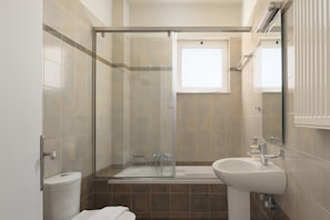 Une salle de bain moderne avec une douche à parois de verre, un lavabo blanc et des toilettes.