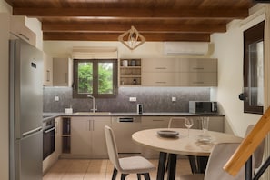 A modern kitchen with a dining area, featuring a built-in oven, microwave, and a wooden ceiling.