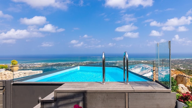 Une piscine offrant une vue dégagée sur l’océan et sur le paysage urbain au loin.