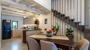 Une cuisine moderne avec un coin repas, comprenant une table en bois, des chaises et un escalier avec des rampes en métal.