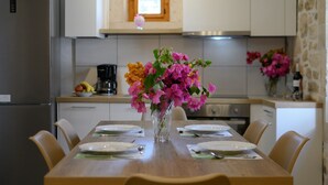 A dining table set with plates, a vase of flowers, and a bowl of fruit. - View Mare Maroulas Villa (Rethymno)
