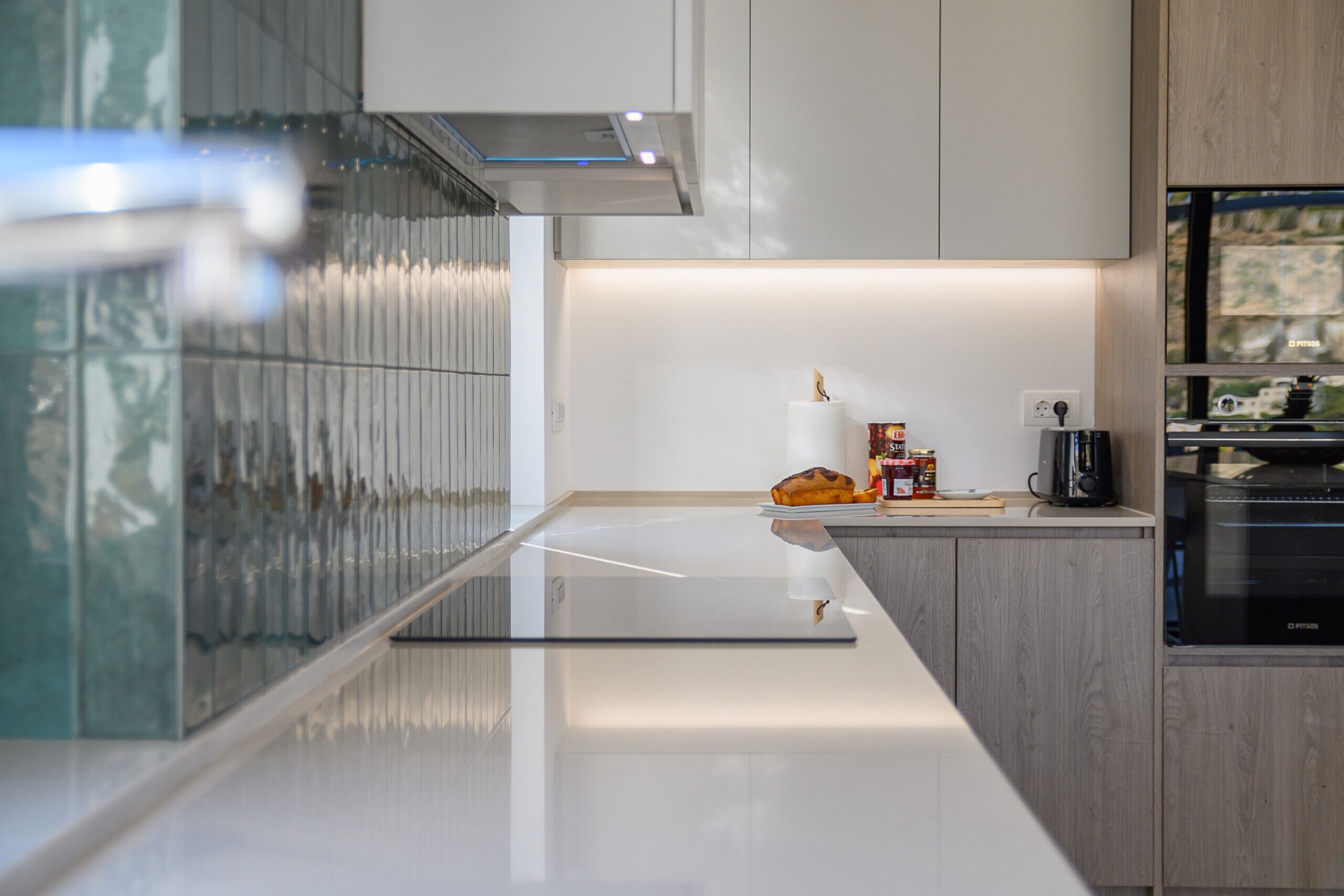 A modern kitchen with a glass countertop, stainless steel appliances, and wooden cabinetry.