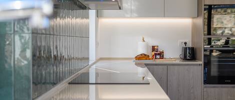 A modern kitchen with a glass countertop, stainless steel appliances, and wooden cabinetry.