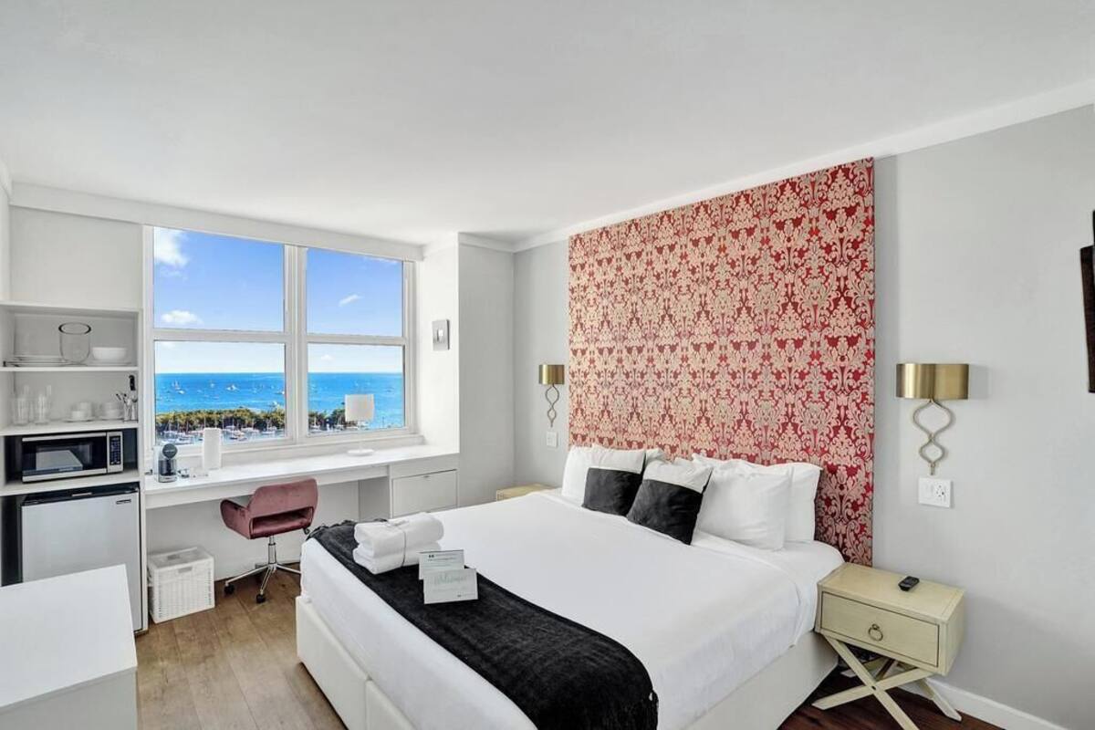 A hotel room with a bed, desk, and a view of the ocean.