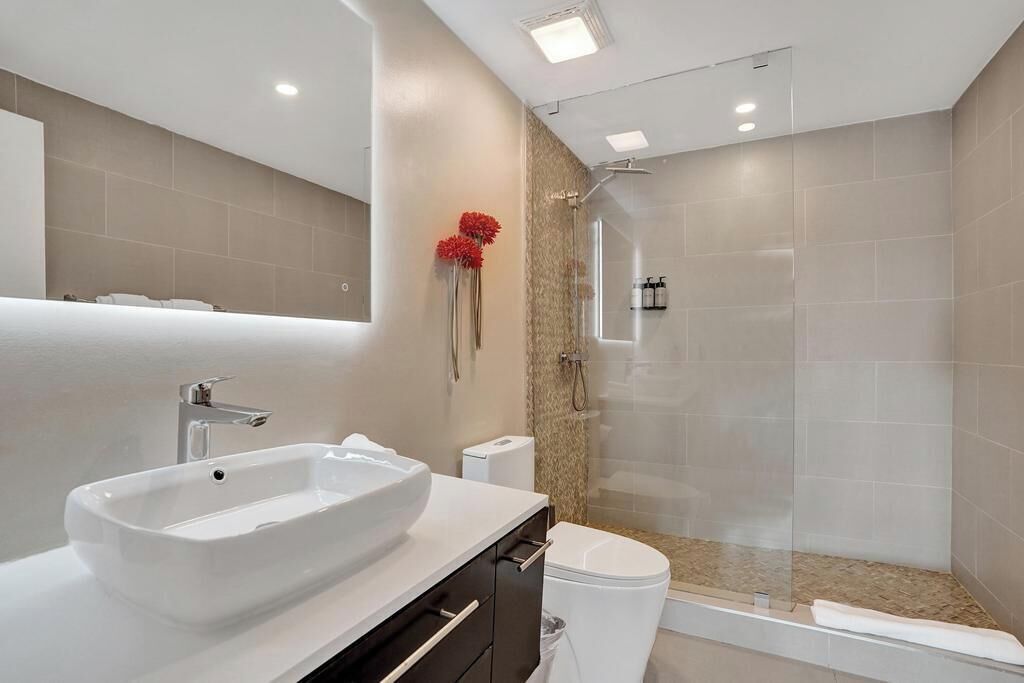 Un baño moderno con un lavamanos grande y blanco, un inodoro y una cabina de ducha de vidrio.