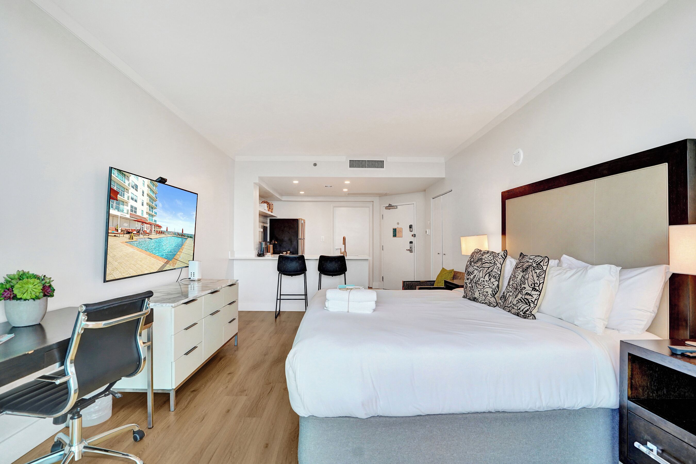 Une chambre d’hôtel avec un lit, un bureau, une chaise et un tableau au mur.
