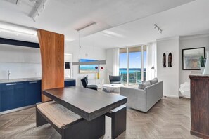 A modern living space with a dining area, kitchen, and a large window offering a view. - Stay Hospitality - Coconut Grove (Miami)