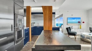 Eine moderne Küche mit Edelstahlgeräten, einer Holztheke und Blick auf den Ozean.