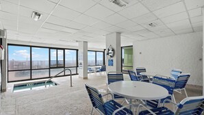 Un espace aménagé au bord de la piscine, avec des chaises bleues et blanches, une piscine et une vue sur l’océan.
