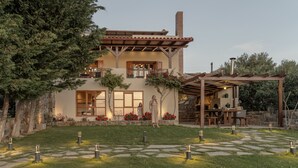 Een tweelaags huis met een terras, buitenmeubels en een pad van stenen.