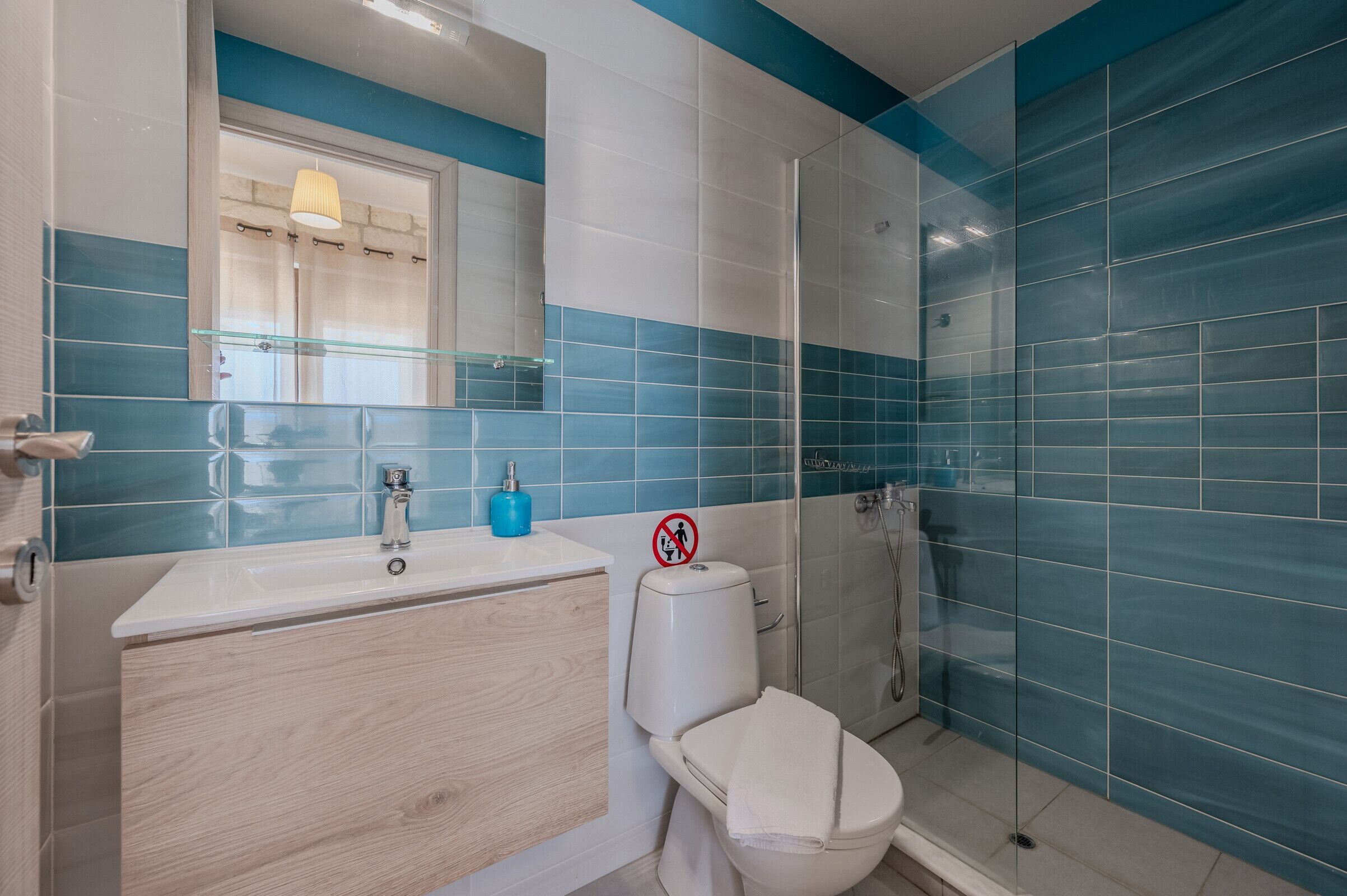 Un baño con un lavamanos blanco, un espejo, un inodoro y una ducha.