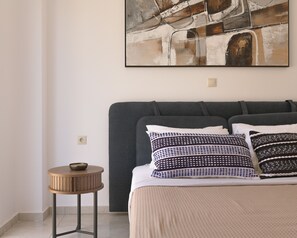 Ein Schlafzimmer mit einem Bett, Kissen, einem runden Holztisch und einem Bild an der Wand.
