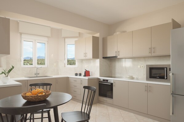 A modern kitchen with a dining table, chairs, a microwave, oven, and a sink.