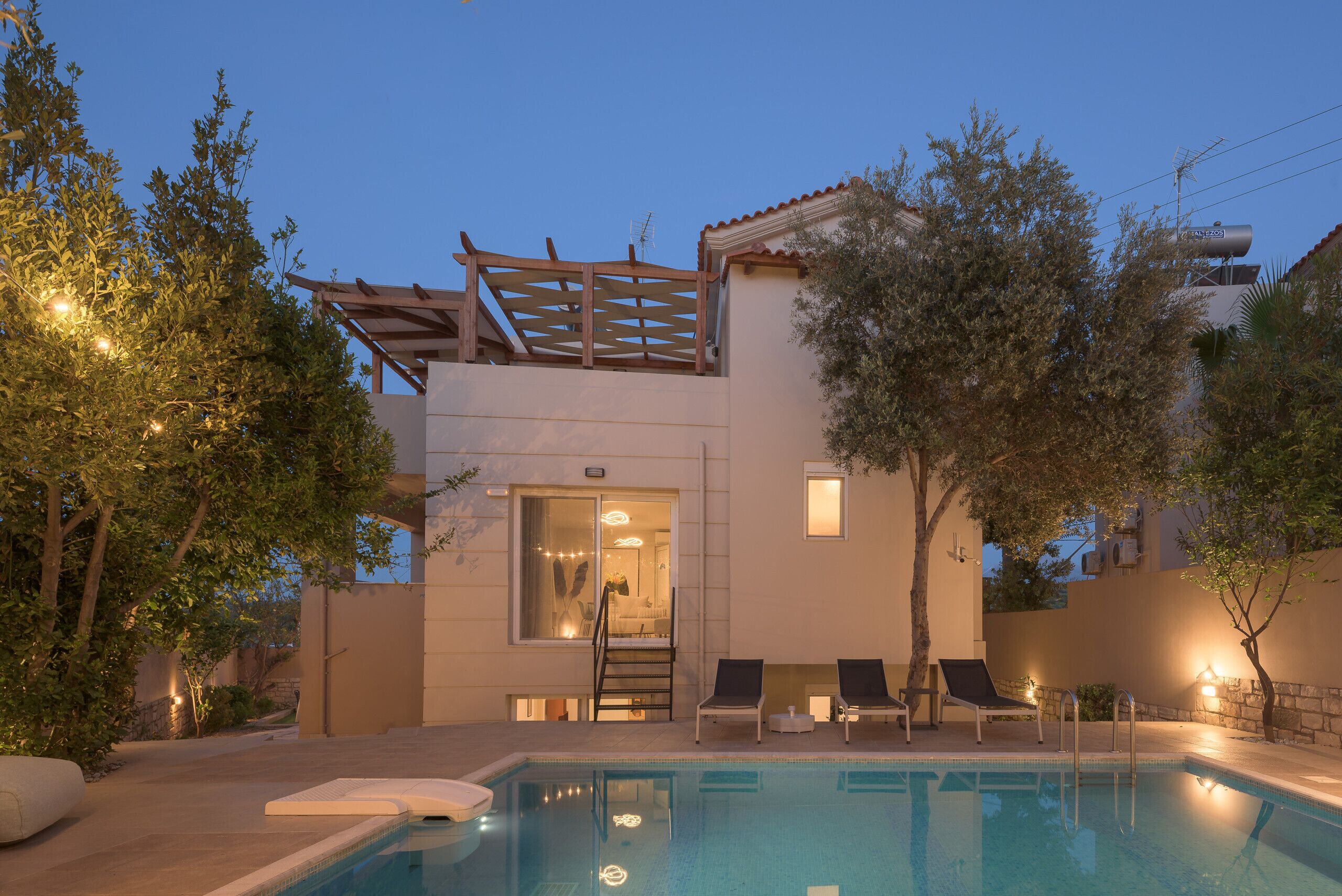 A pool area with a pergola, lounge chairs, and a staircase leading to an upper level.