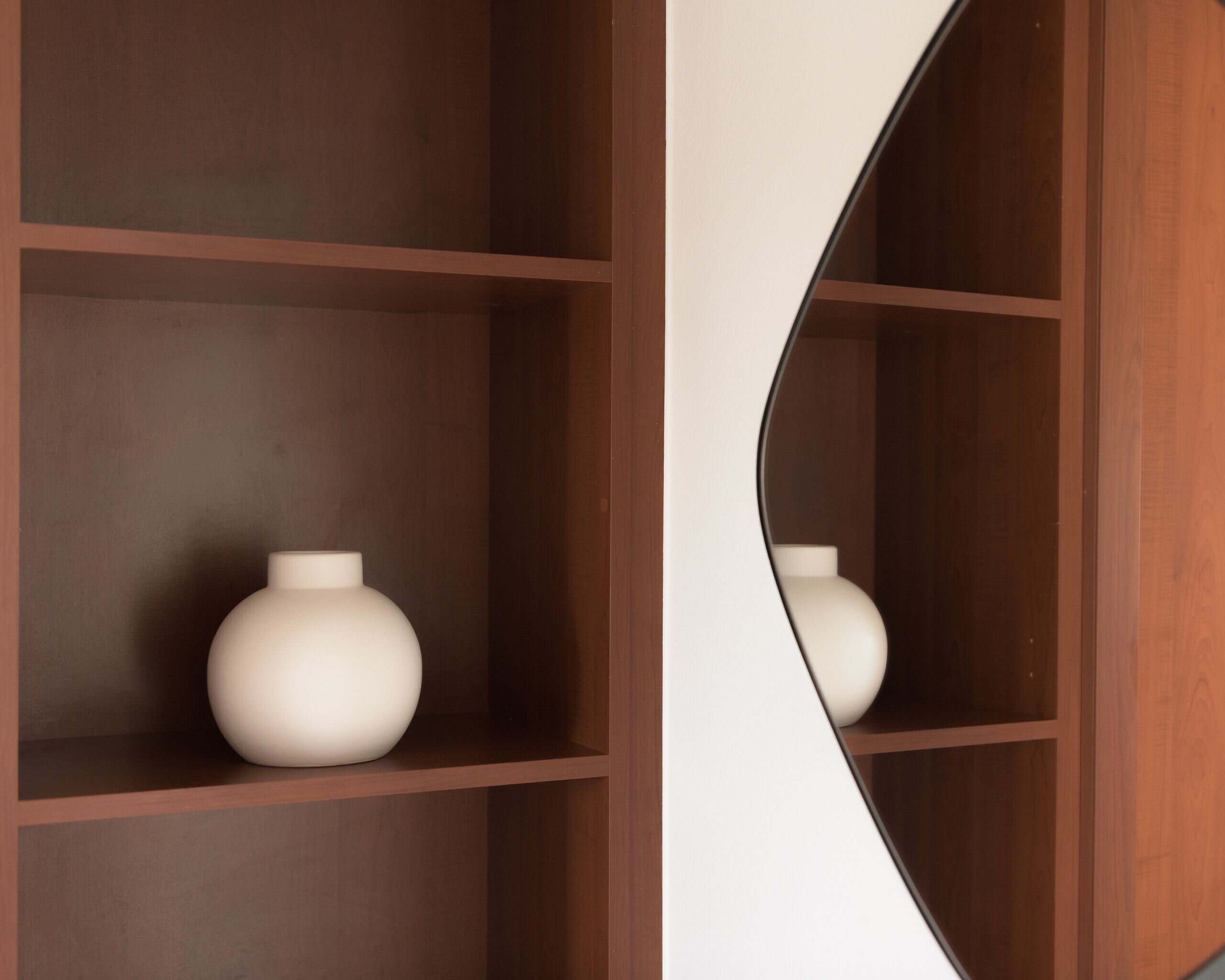 Une étagère en bois avec un vase blanc.