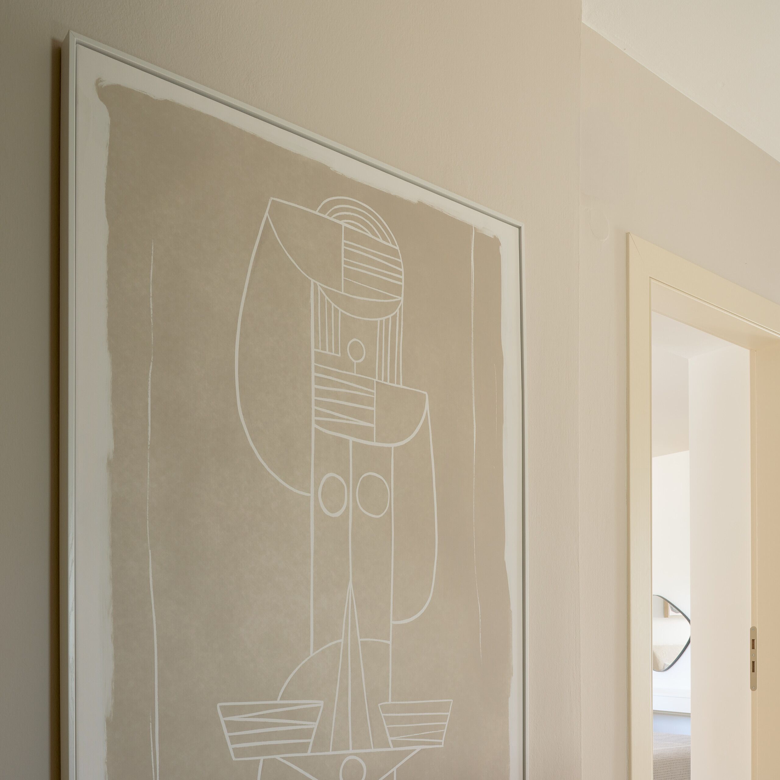 Een minimalistisch ingerichte kamer met een groot abstract schilderij aan de muur, een deur naar een andere kamer en een zichtbare lichtschakelaar.
