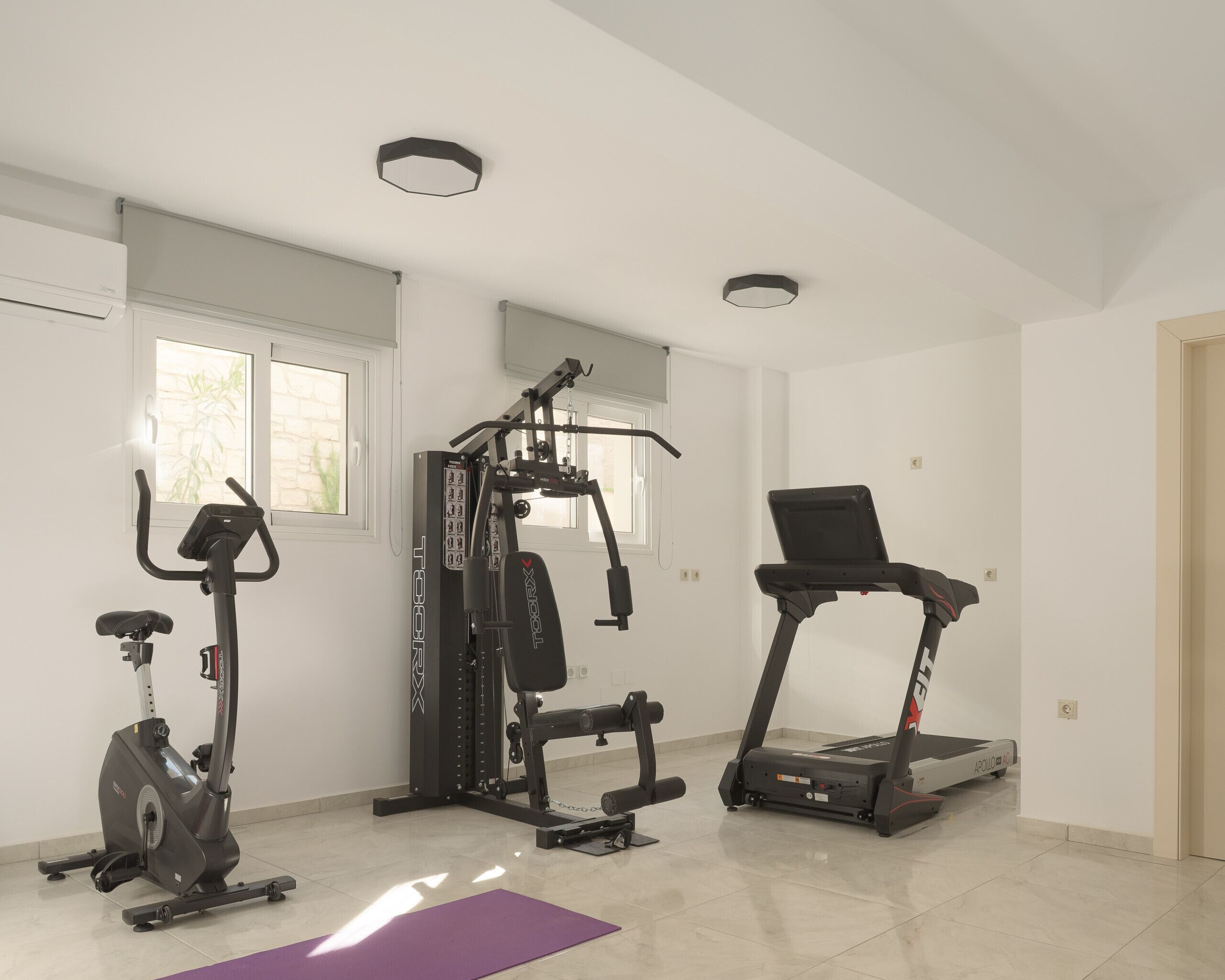 Un gimnasio en casa con una elíptica, una máquina de pesas y una cinta de correr.