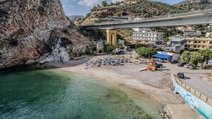 A coastal area with a beach, clear water, a bridge, and buildings in the background. - Villa Nikos (Malevizi)