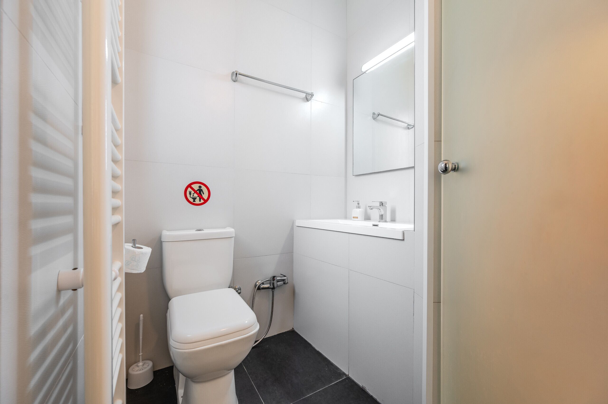 Une petite salle de bain propre, équipée de toilettes, d’un lavabo et d’un miroir.