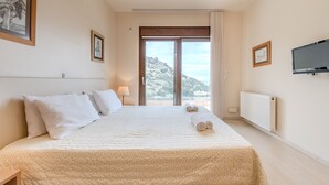 A hotel room with a large bed, a TV, and a view of the mountains. - Villa Paris (Malevizi)