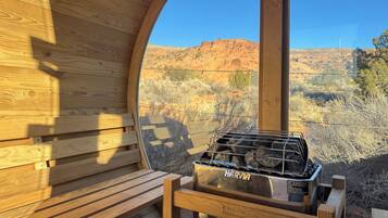 A wooden interior with a Harvia grill, a bench, and a view of a desert landscape.