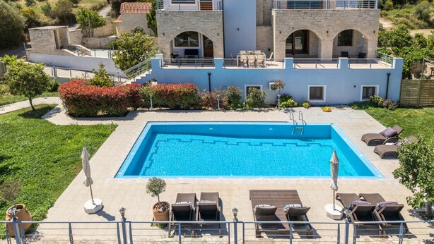 A modern villa with a swimming pool, outdoor seating, and a view of the surrounding landscape. - Arios Lux Villa (Rethymno)