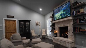 A living room with a fireplace, comfortable seating, and a large flat-screen TV.