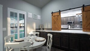 A modern kitchen with dark cabinets, a white countertop, and a sliding barn door.