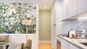 A modern kitchen with white cabinets, a marble countertop, and a wall-mounted lamp.