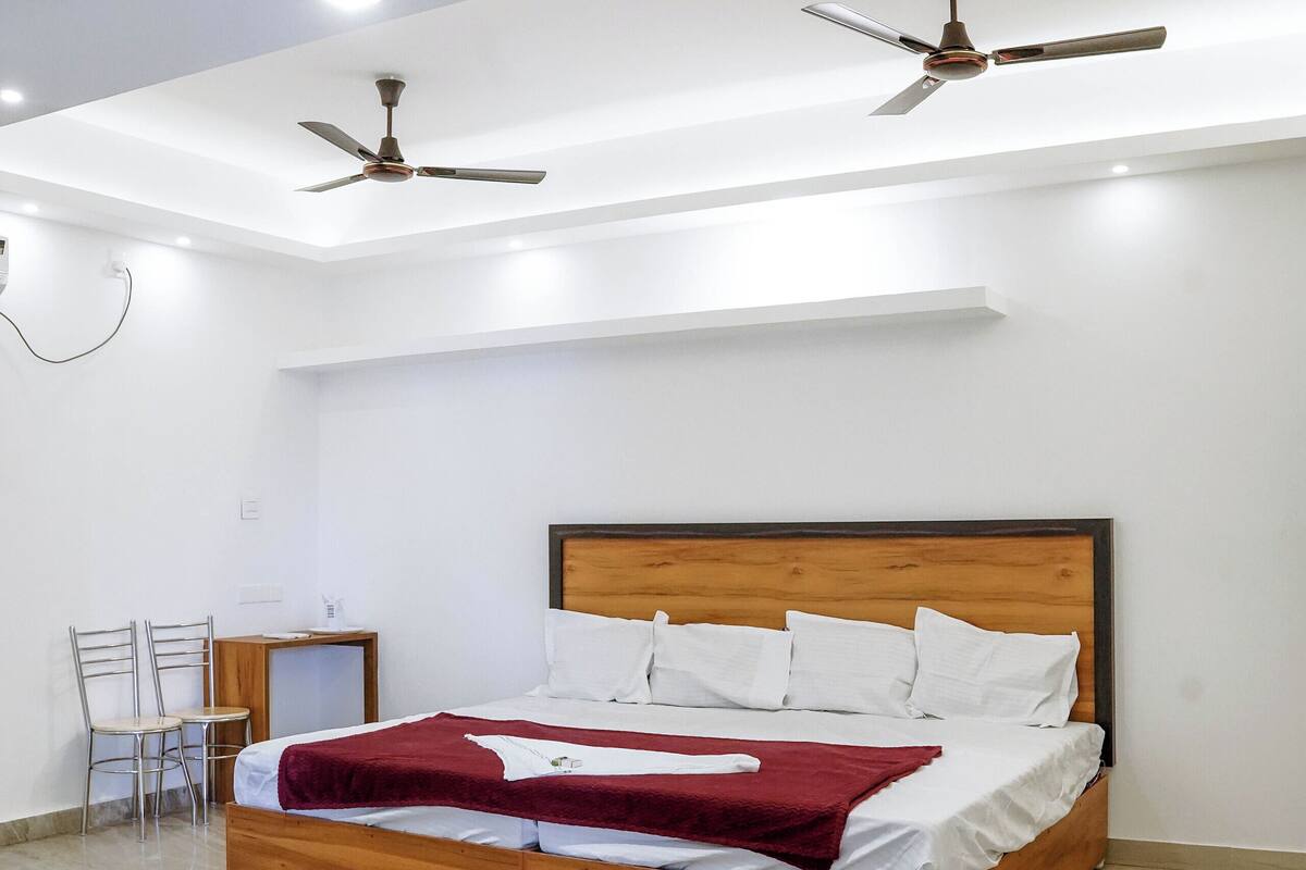 Ein Schlafzimmer mit einem hölzernen Bett, einem Deckenventilator und einem Schreibtisch mit Stuhl.