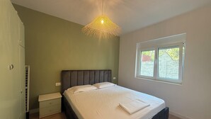 A bedroom with a bed, bedside table, and a window.