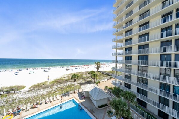 A hotel with a pool, beach view, and multiple balconies.