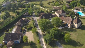 An aerial view of a rural property with multiple buildings, a swimming pool, and surrounding greenery.